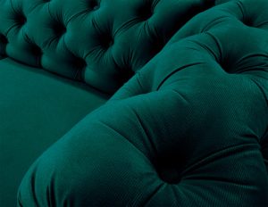 Close-up view of the dark green corner sofa, highlighting its tufted upholstery and plush texture.